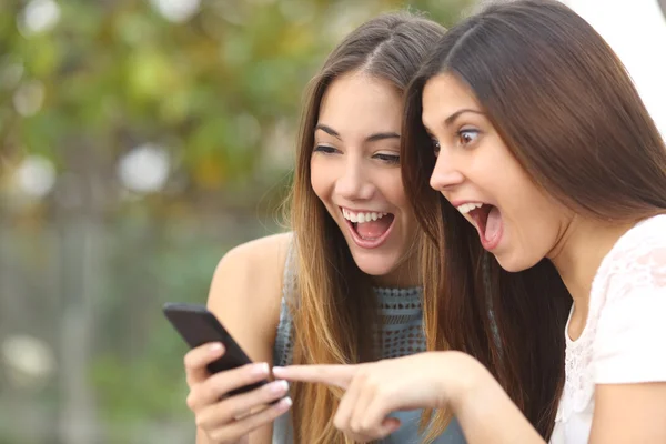 Euforisk vänner titta på video på en smartphone — Stockfoto