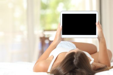 Kız boş tablet ekran gösterilen bir yatakta