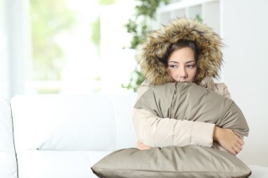 Woman warmly clothed in a cold home clipart