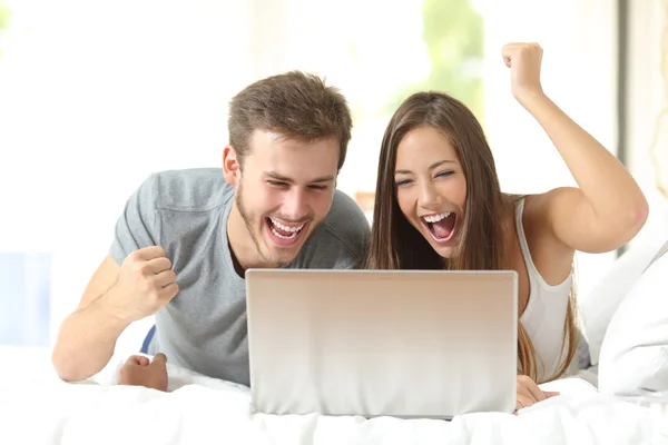 Casamento eufórico ganhando com um laptop em casa — Fotografia de Stock