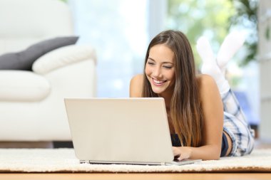 Girl online browsing a laptop at home clipart