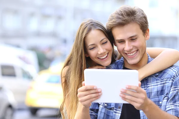 Casal feliz compartilhando um tablet na rua — Fotografia de Stock