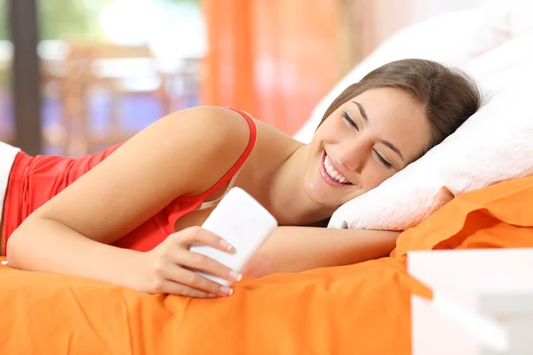 Adolescente usando um telefone inteligente na cama — Fotografia de Stock