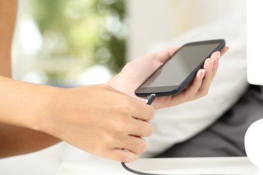 Eller kadın bir akıllı telefon bir şarj cihazı takarak