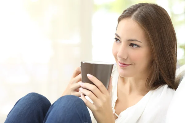 Pensive girl holding a coffee cup at home — Stock Photo, Image