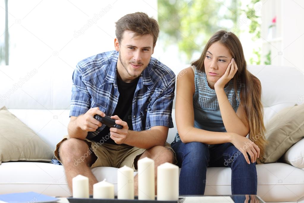 Man playing video games and girlfriend bored beside