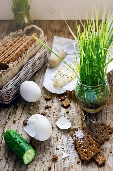 Hard boiled eggs, cucumber, camembert cheese, germinated seeds of grass and wholegrain crisps on the vintage wooden table — Stock Photo, Image