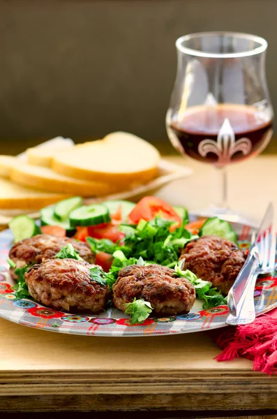 Koteletter med friske grøntsager salat, brød og glas vin - Stock-foto