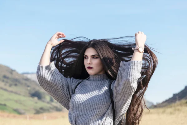 pretty brunette girl with very long hair over a blue sky