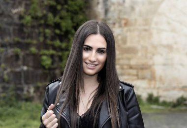 Açık havada yün kazak giyen genç bir kadının portresi.