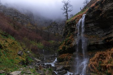waterfalls of the birth of the nervion in the north of spain, in the province of alava on a cloudy day clipart