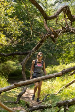 Ormanda yürüyen bir kadın kameraya yaklaşıyor.