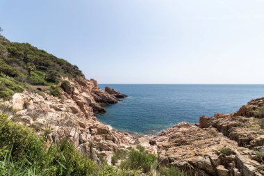 Akdeniz manzarası güneşli bir günde kayalık bir sahil, mavi bir deniz ve açık bir gökyüzünü gösteriyor.