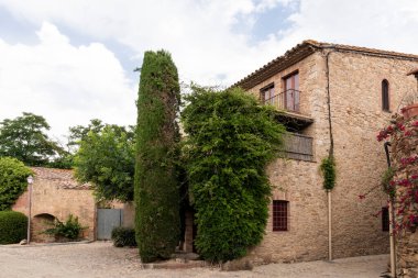 Antik taş binalar ve selvi ağacı dostlarda, İspanya 'da bir kaldırım taşı caddesini kaplıyor.