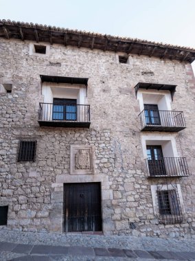 Geleneksel balkonların ve kolsuz antika bir kürkün bulunduğu tarihi bir binanın eski taş cephesi.