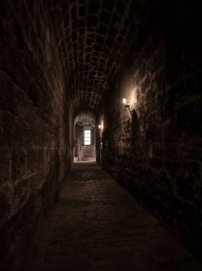 Ortaçağ kavisli kaldırım taşı koridoru lambalarla aydınlık bir pencereden açılıyor.