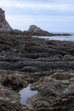 Değişik jeolojik oluşumlara ve gökyüzünü yansıtan suya sahip Rocky kıyı şeridi