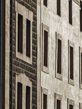 Yinelenen taş dokusu ve dar dikey pencerelerle ön cephe oluşturma