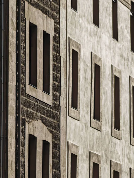 Yinelenen taş dokusu ve dar dikey pencerelerle ön cephe oluşturma