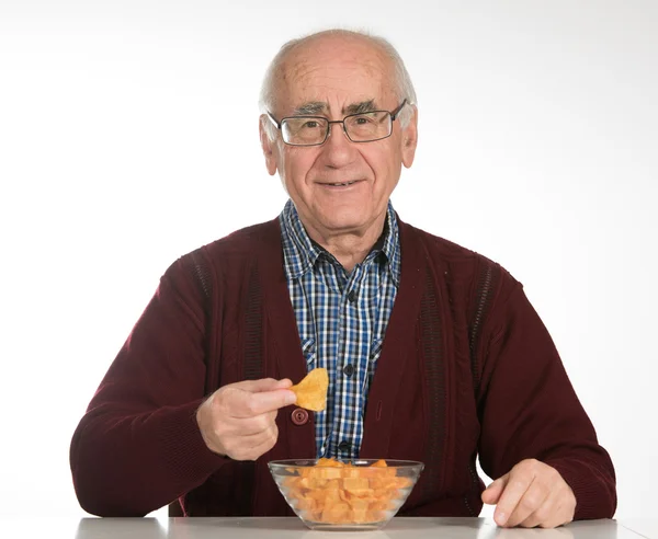 Starý muž jíst chipsy — Stock fotografie