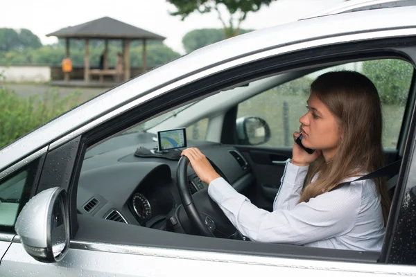 若い女性の車の運転と携帯電話で話しています。 — ストック写真