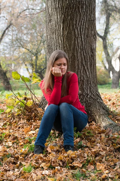 Ledsen flicka sitter i en park — Stockfoto