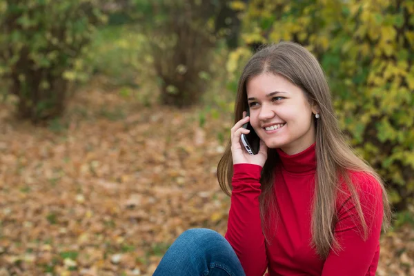 Young woman talking on mobile phone in fall — Stock Photo, Image