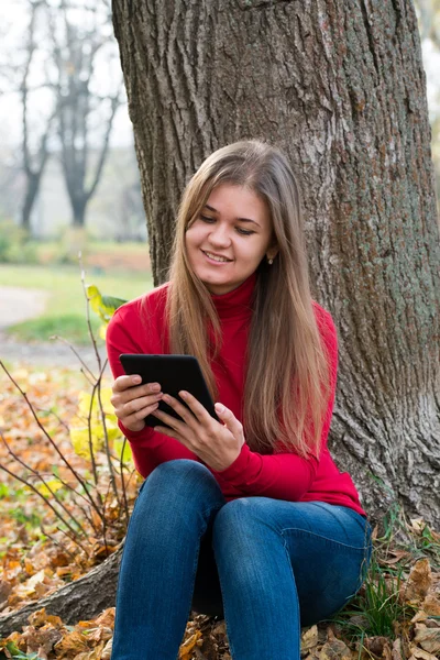 电子书在秋天公园的年轻女子 — 图库照片