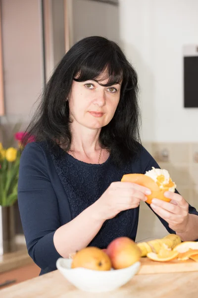 Kadın bir portakal ile mutfakta — Stok fotoğraf