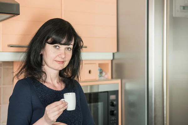 Sorrindo mulher bebendo café na cozinha — Fotografia de Stock