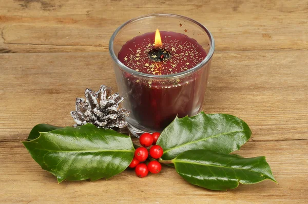 Brennende Weihnachtskerze Auf Rustikalem Holz Mit Stechpalme Und Schneebedecktem Tannenzapfen — Stockfoto