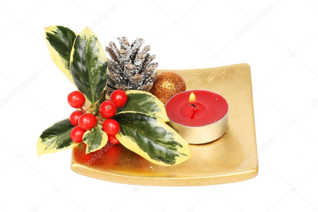 Christmas table centerpiece, variegated holly, pinecone, bauble and candle on a gold dish isolated against white