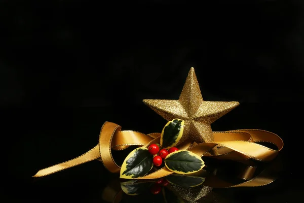 Dekoracja Świąteczna Zwinięta Złota Wstążka Holly Złotą Gwiazdką Czarnym Tle — Zdjęcie stockowe