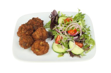 Beyazlara karşı izole edilmiş tabakta falafel ve salata.