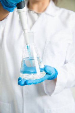 Tıbbi teknoloji araştırma laboratuvarında deney tüpüyle çalışan bir bilim adamı. Koronavirüs, covid-19 aşısı üzerinde çalışan kimyager ya da biyogenetik doktor.