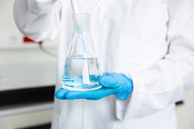 Tıbbi teknoloji araştırma laboratuvarında deney tüpüyle çalışan bir bilim adamı. Koronavirüs, covid-19 aşısı üzerinde çalışan kimyager ya da biyogenetik doktor.