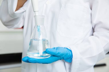 Tıbbi teknoloji araştırma laboratuvarında deney tüpüyle çalışan bir bilim adamı. Koronavirüs, covid-19 aşısı üzerinde çalışan kimyager ya da biyogenetik doktor.