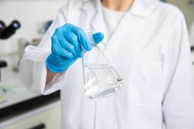 Tıbbi teknoloji araştırma laboratuvarında deney tüpüyle çalışan bir bilim adamı. Koronavirüs, covid-19 aşısı üzerinde çalışan kimyager ya da biyogenetik doktor.