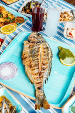 Izgara balık, salata ve sebze. Deniz ürünleri, ızgara et, meze, rakı, uzo, aperatifler ve salatalar Yunan ya da Türk Balık Restoranı 'nda akşam yemeği ya da sahilde öğle yemeği için masaya..