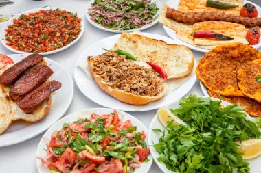 Yemek masasındaki Türk restoranında kolaj ya da yemek takımı. Kebap, lahmacun, sucuk ve salata..