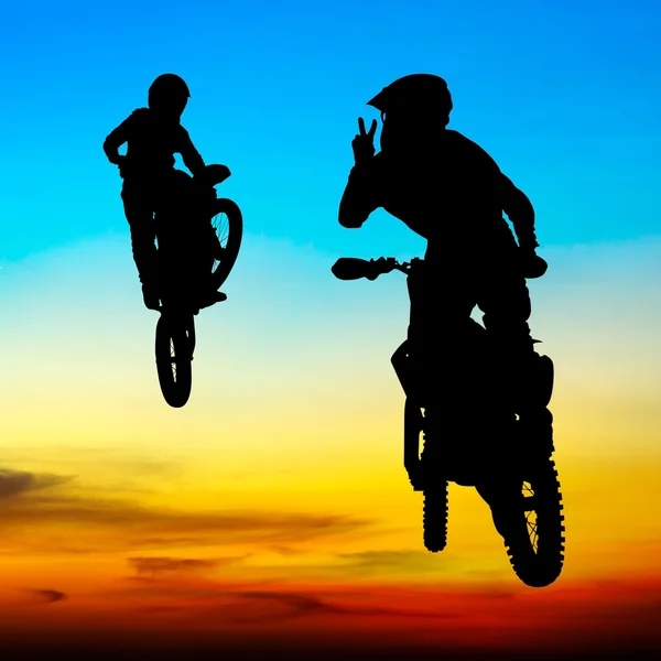 Silhouette des Motocross-Fahrers springt bei Sonnenuntergang in den Himmel — Stockfoto