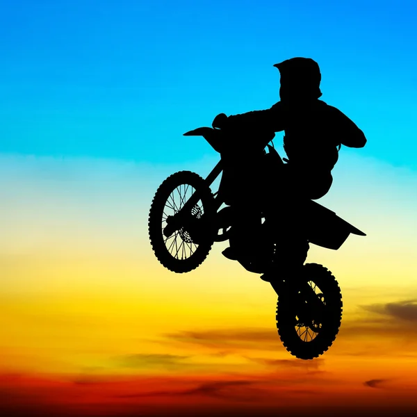 Silueta motorkáře skočit na obloze při západu slunce — Stock fotografie