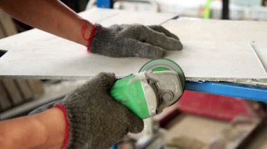 Açı öğütücüyle fayans kesen bir işçi.