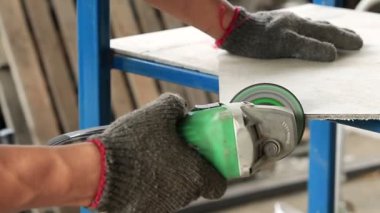 Açı öğütücüyle fayans kesen bir işçi.