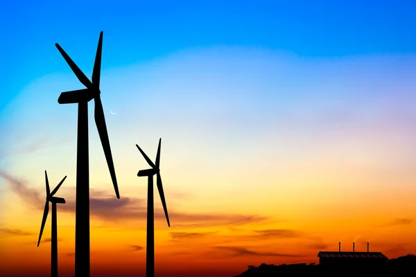 Silhouette wind turbine generator with factory emissions of carb — Stock Photo, Image