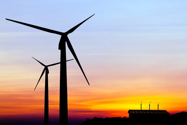 Silhouette wind turbine generator with factory emissions of carb — Stock Photo, Image