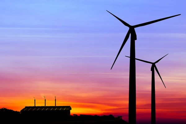 Silhouette wind turbine generator with factory emissions of carb — Stock Photo, Image