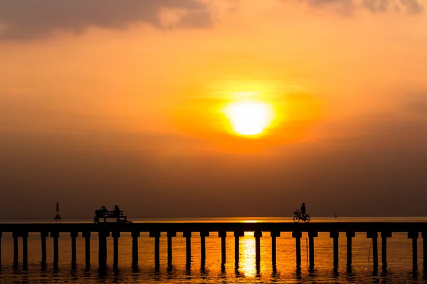 Siluet kişi binmek bisiklet ve güneşler köprüde oturan — Stok fotoğraf