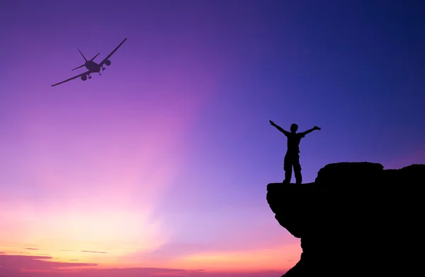 Silhouette eines Mannes auf dem Felsen und Silhouette Verkehrsflugzeug — Stockfoto