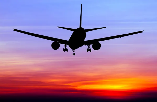 Avión comercial Silhouetted volando al atardecer — Foto de Stock